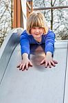 Young Girl Lies Forward On Slide Stock Photo