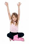 Young Girl Seated On Floor Posing With Raised Arms Stock Photo