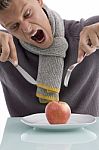 Young Man Going To Eat Apple With Fork And Knife Stock Photo