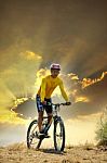 Young Man Riding Moutain Bike Mtb On Land Dune Against Dusky Sky Stock Photo