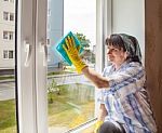 Young Smiling Woman Washes A Window Stock Photo