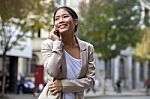 Young Woman And Smart Phone Walking On Street Stock Photo