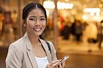 Young Woman And Smart Phone Walking On Street Stock Photo