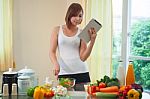 Young Woman Following Recipe On Digital Tablet Stock Photo