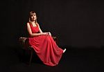 Young Woman In Red Dress Sitting On A Chair Stock Photo