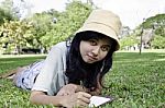 Young Woman Lies On Green Summer Meadow With Book Stock Photo