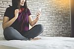 Young Woman Sitting In Her Bed And Listening Music In Her Bedroo Stock Photo