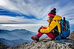 Young Woman Sitting On The Hill Of High Mountains Stock Photo