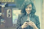 Young Woman Using Mobile Phone Walking On Street Stock Photo