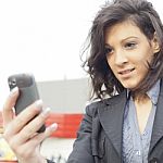 Young Woman With Cell Phone Walking, Blured Business Building In Stock Photo