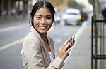 Young Woman With Smile And Smart Phone  On Street Stock Photo