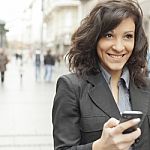 Young Woman With Smile And Smartphone Walking On Street Stock Photo