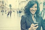 Young Woman With Smile And Smartphone Walking On Street Stock Photo